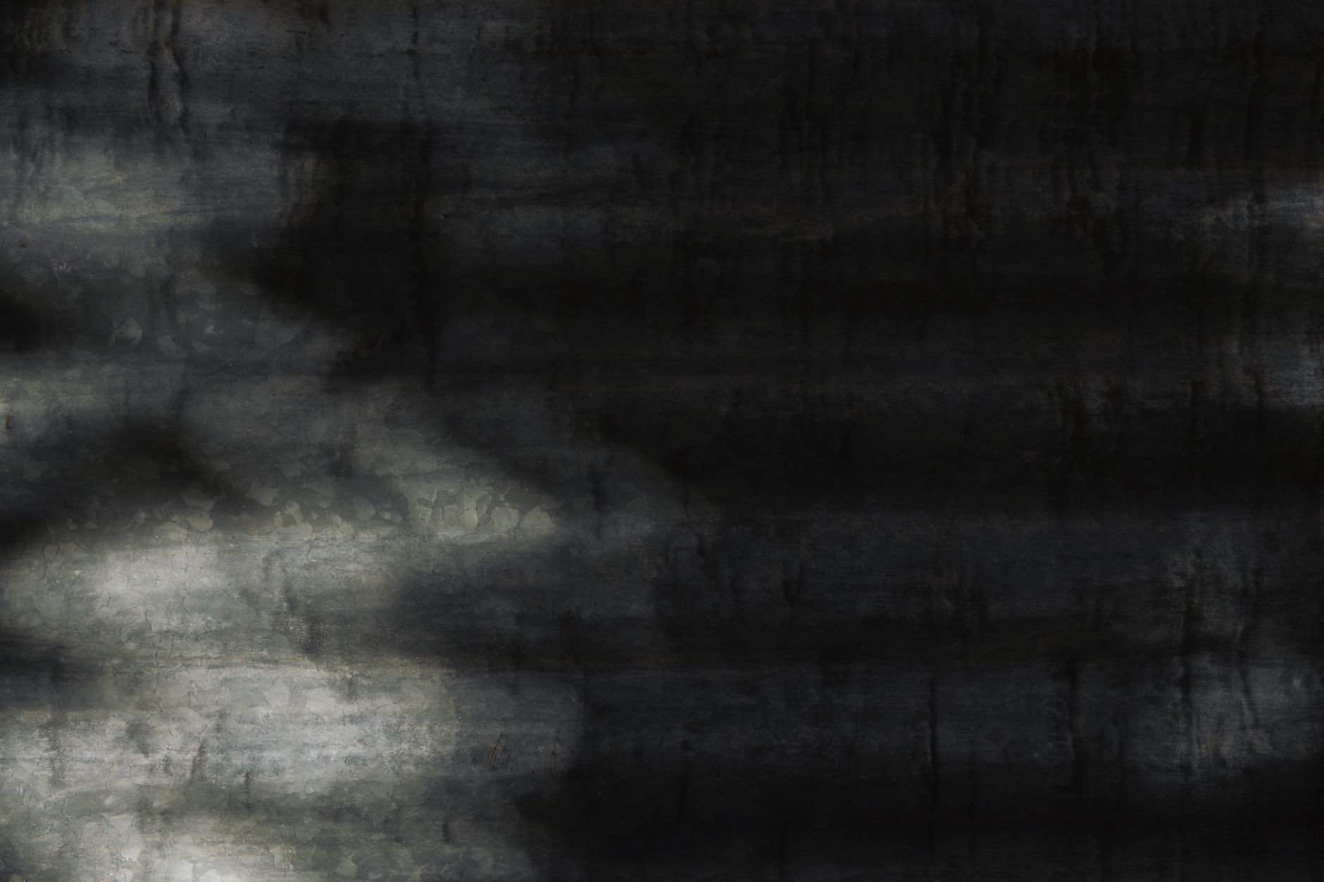 Close-up of a dark metal surface with abstract shadows and textures.